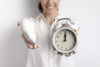 defocused smiley woman holding light bulb clock