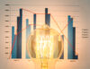 close up illuminated light bulb with chart background